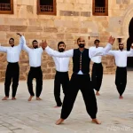 요르단 전통음악과 춤 - **Prompt:** A dynamic group of young and middle-aged Jordanian men performing a traditional Dabke da...